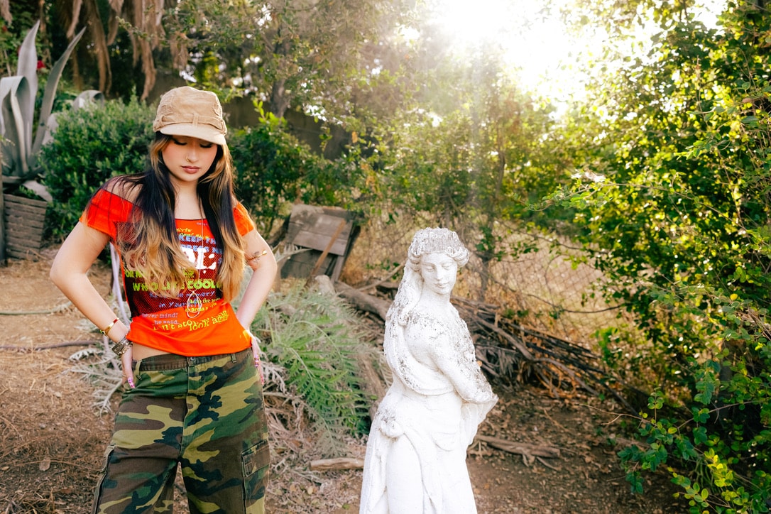Sienna Melgoza in a garden beside a white statue