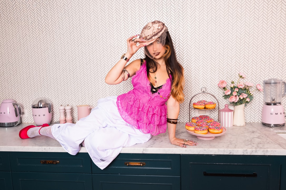 Sienna Melgoza in a pink outfit in a retro kitchen